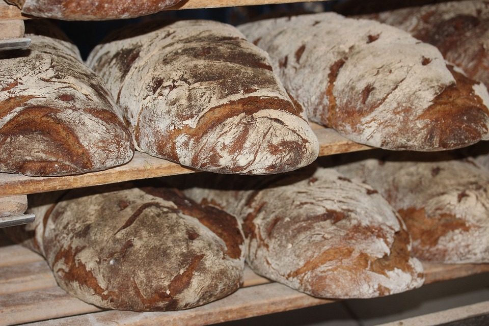 Rustieke bruine broden op houten bakkersrekken