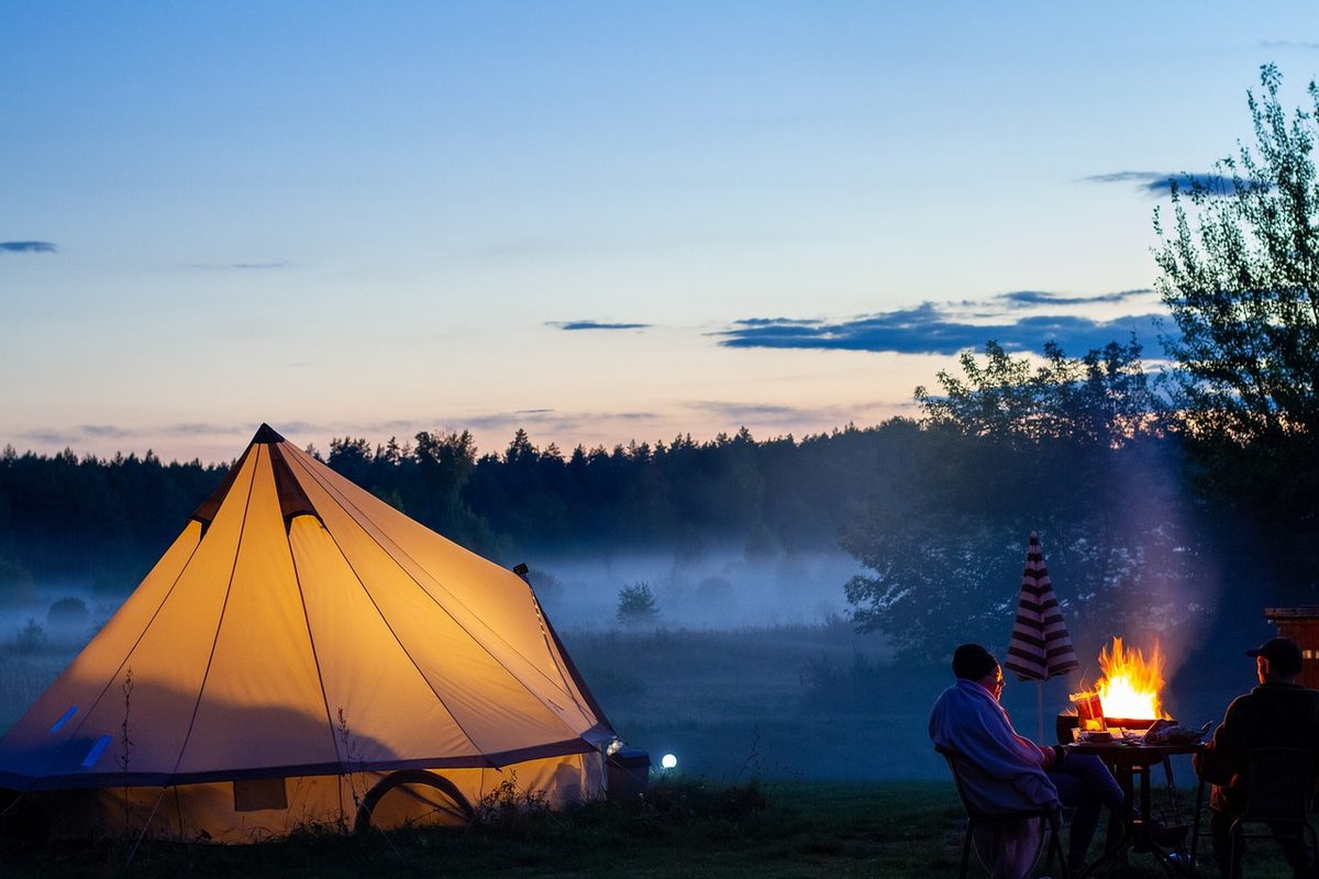 Verlichte tent en kampvuur in de schemering