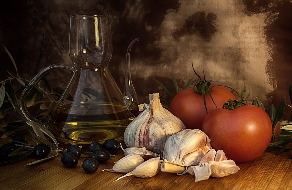 Stilleven met olijfolie, knoflook, olijven en tomaten
